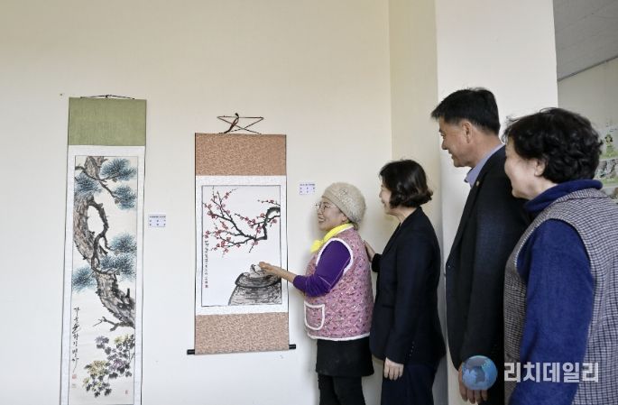 영인면 행정복지센터 층간 통로에 전시된 문인화반 작품을 주민들이 감상하고 있다.